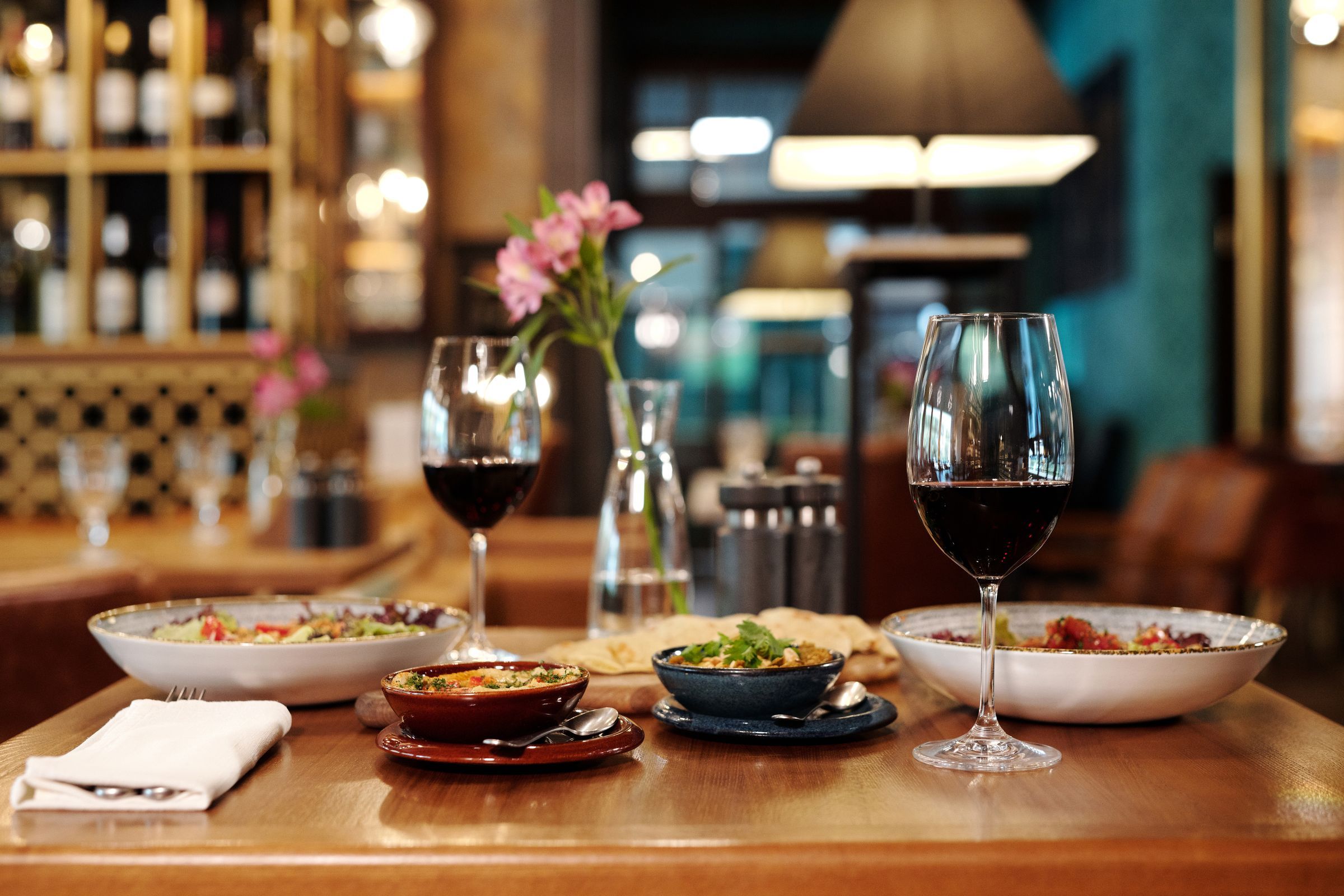 Tavola apparecchiata in sala, con piatti e vino rosso